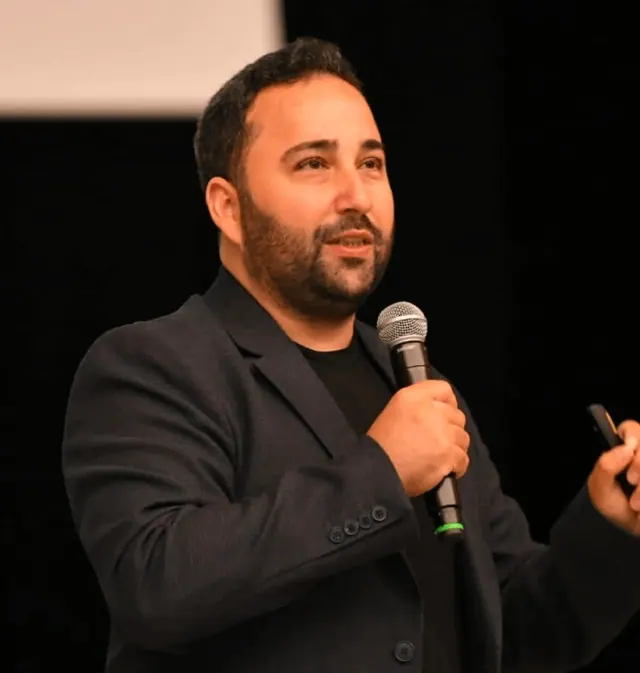 Kaan Gülten sahnede mikrofonla konuşurken