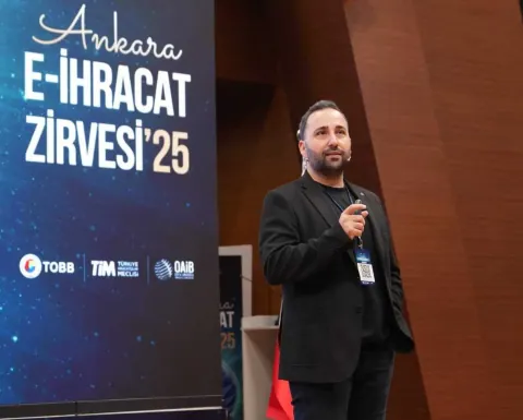 Kaan Gülten speaking at a lectern in front of an event banner