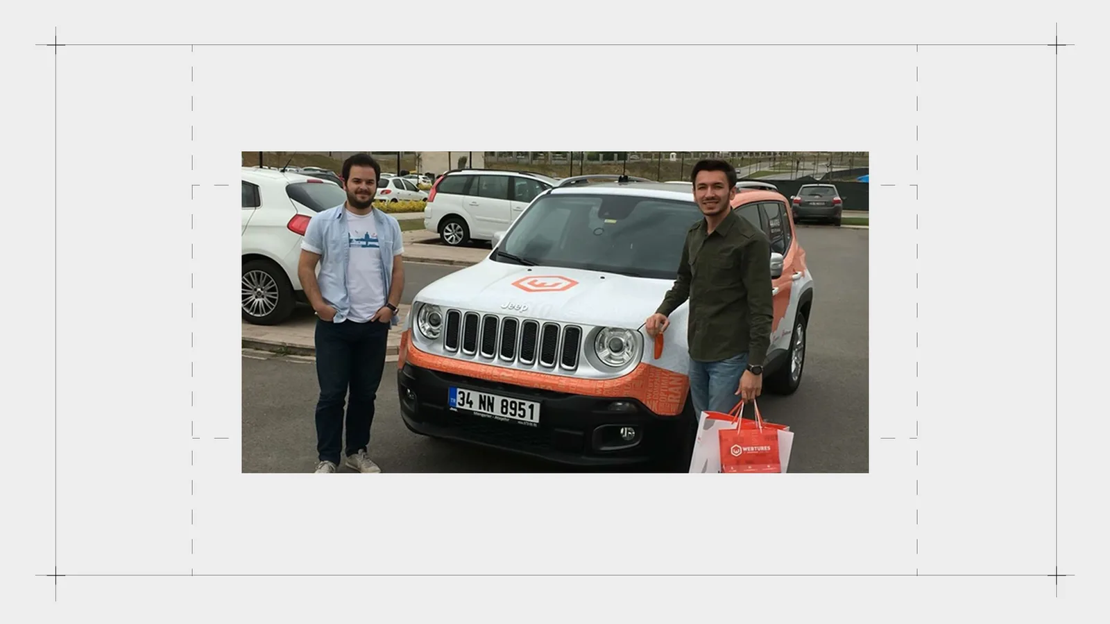 Kaplamalı Jeep önünde iki kişi, elinde hediye çantası.